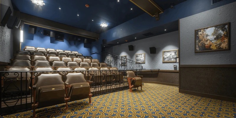 A view of the interior of the John T. Taylor Screening Room from the perspective of the film screen looking out over the empty 43 seat microcinema. Framed historical photos of the Tampa Theatre are lining the entrance ramp walkway.